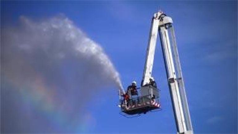 Feuerwehrmann beim Löschen am Hebekran