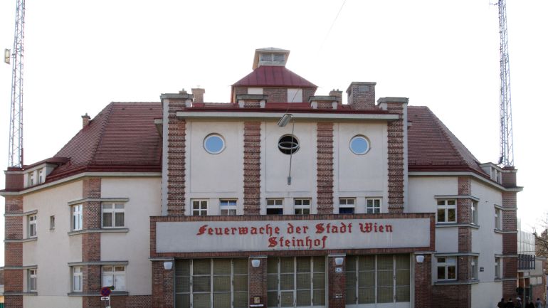 Blick auf das zweistöckige Haus mit Balkon, drei Toren und Masten auf der Seite