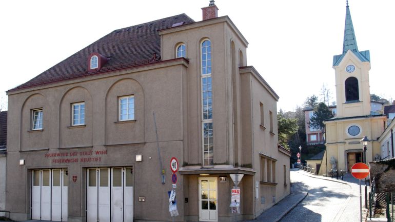 Eckansicht der einstöckigen Wache, Eingangstür mit langem, großen Fenster darüber, zwei Tore