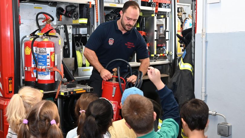 copyright: Stadt Wien/Feuerwehr Feuerwehrmann präsentiert Kindern einen Feuerlöscher im Rahmen einer Wacheführung