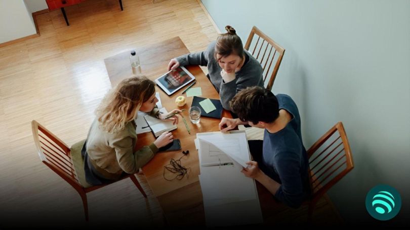 Drei Jugendliche an einem Tisch machen sich Notizen