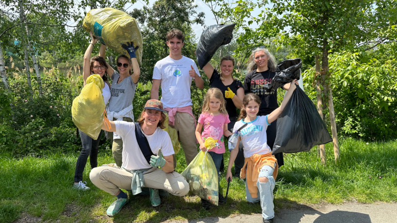 Kinder, Jugendliche und Erwachsene halten volle Müllsäcke in die Höhe