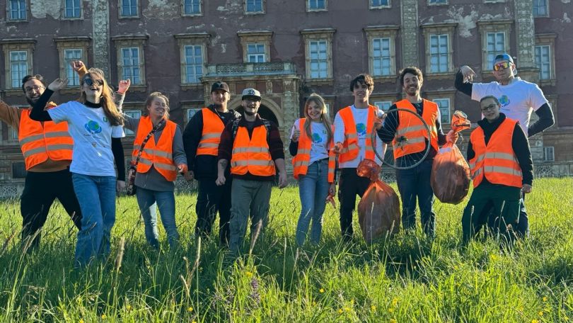 Menschen in Warnwesten halten Müllsäcke in die Höhe