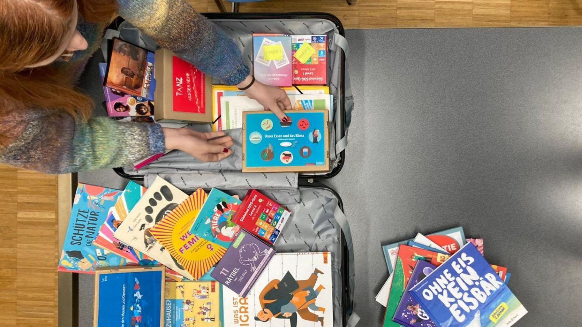 Blick von oben in einen geöffneten Koffer mit diversen Unterrichtsmaterialien