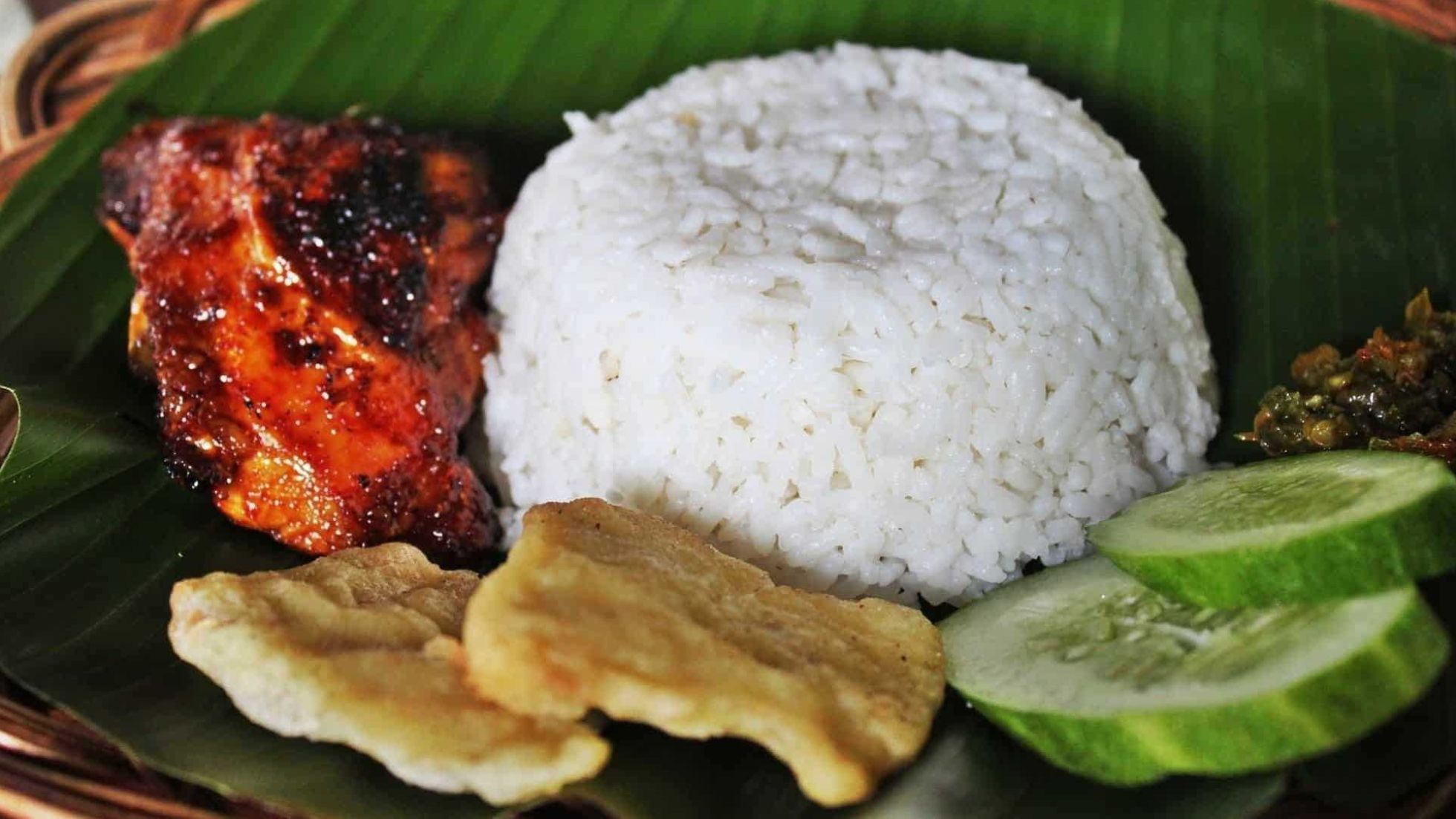 Nahaufnahme von Reis mit Gemüse und gebratenem Fleisch auf einem grünen Blatt