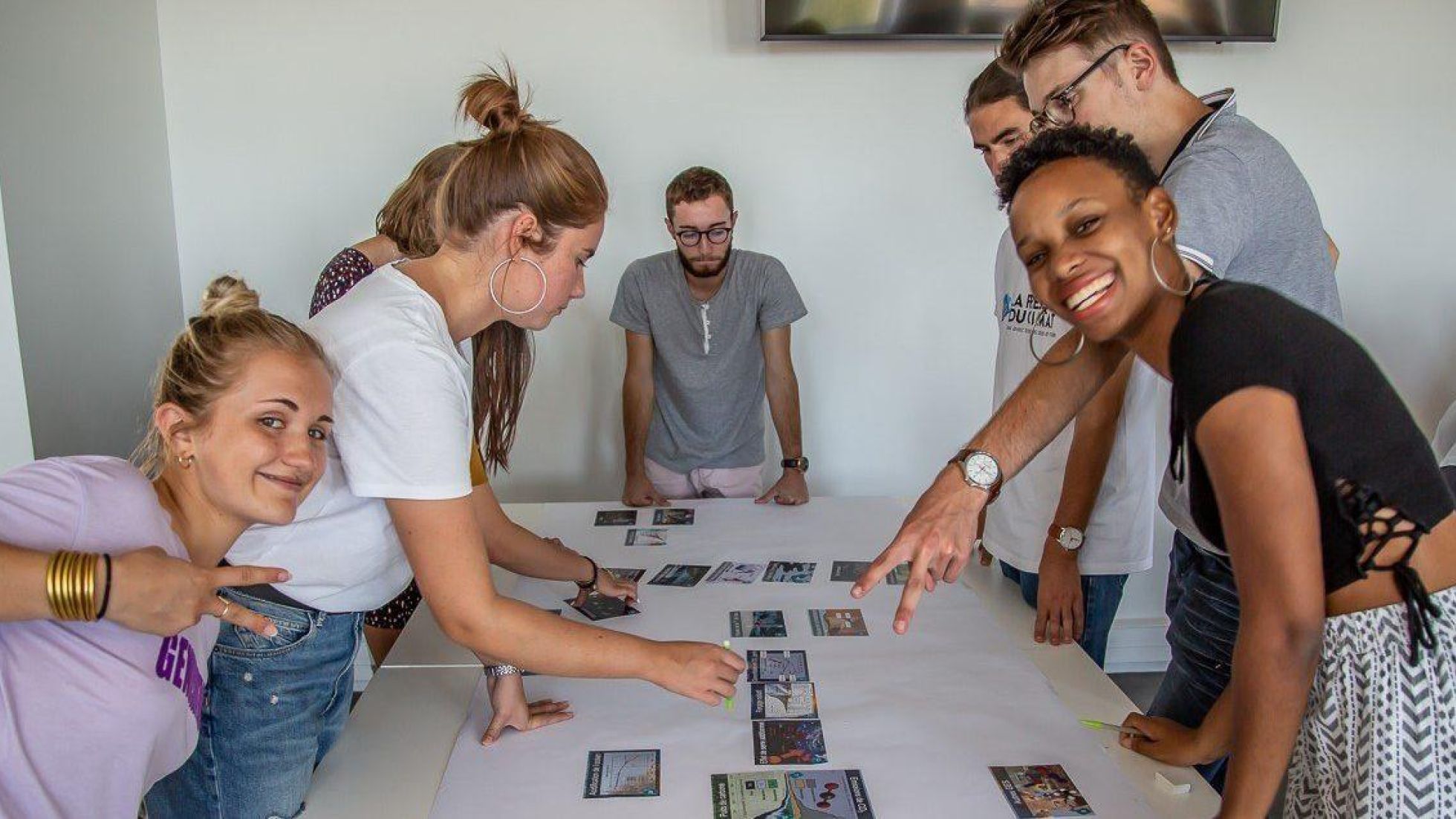 copyright: La Fresque du Climat - Béatrice Ringenbach Eine Gruppe junger Menschen arbeitet an einem Plakat, das vor ihnen am Tisch liegt
