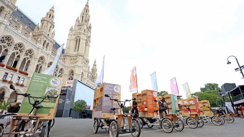 Mehrere Lastenräder mit großen bunten Plakaten stehen vor dem Wiener Rathaus.