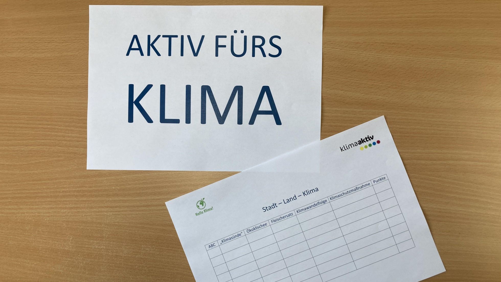 copyright: Österreichische Energieagentur, Severin Ettl 2 Zettel liegen auf einem Tisch, auf einem steht groß "Aktiv fürs Klima"