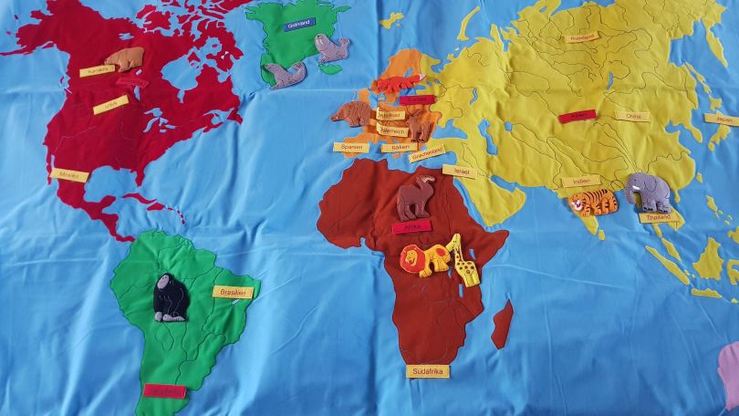 Weltkarte aus Stoff: Nordamerika und Afrika sind rot, Grönland und Südamerika grün und Europa sowie Asien gelb.