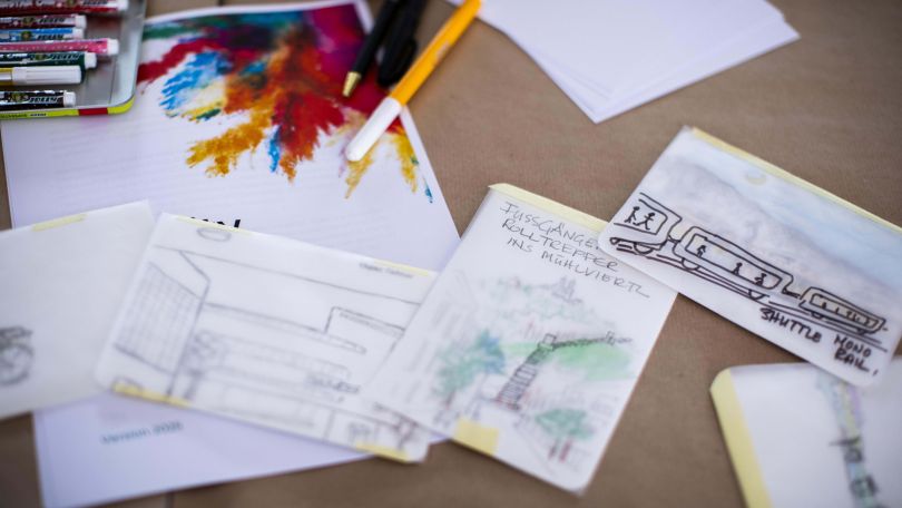 Postkarten, Stifte und Notizzettel liegen auf einem Tisch.