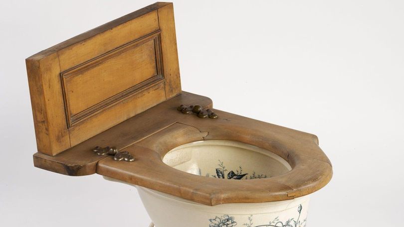 Klobrille aus Holz auf einer Kloschüssel aus Keramik.