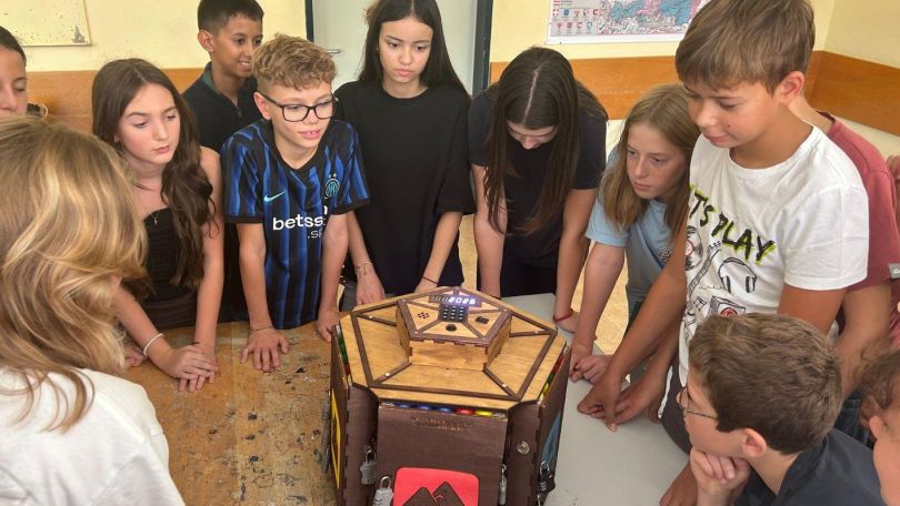 Eine Kindergruppe hat sich rund um eine Holzbox versammelt.