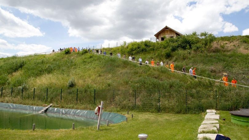 Eine Gruppe Menschen geht einen begrünten Hügel in der Deponie Rautenweg hinunter.