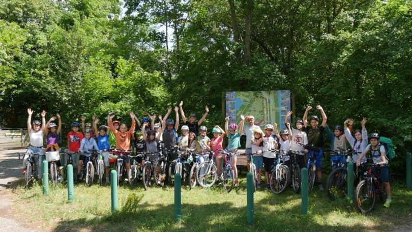 Gruppenfoto von Menschen mit Fahrrädern vor einem Wald