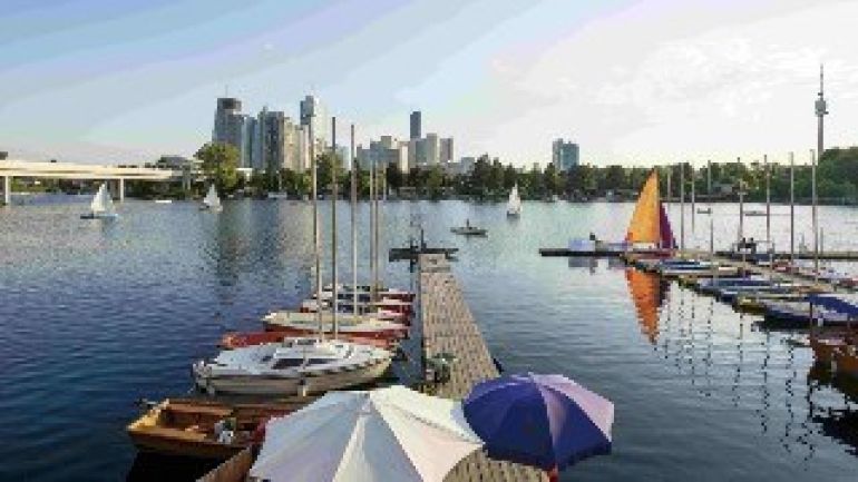Alte Donau mit Steg und Booten, dahinter die Skyline