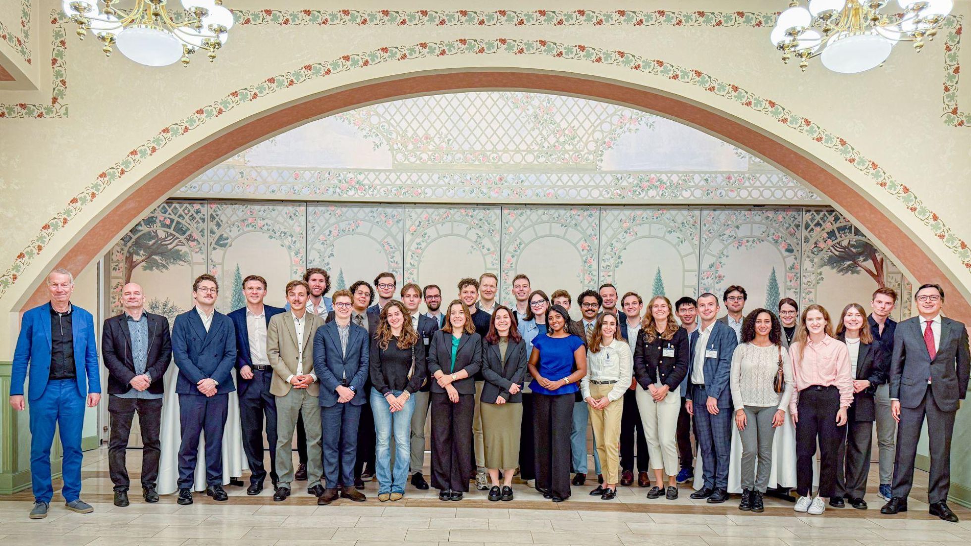 Gruppenfoto in einer Halle mit Rundbogen und Jugendstilornamenten