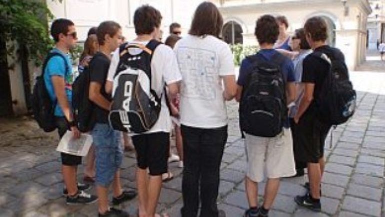 Schulkinder stehen im Kreis und hören zu