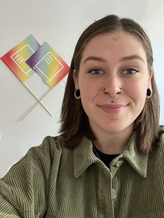 Junge Frau mit 2 Regenbogenfahnen der Stadt Wien