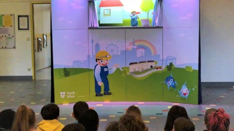 copyright: Wien Kanal Bunte Kasperlbühne mit Kasperl, davor sitzen Kinder