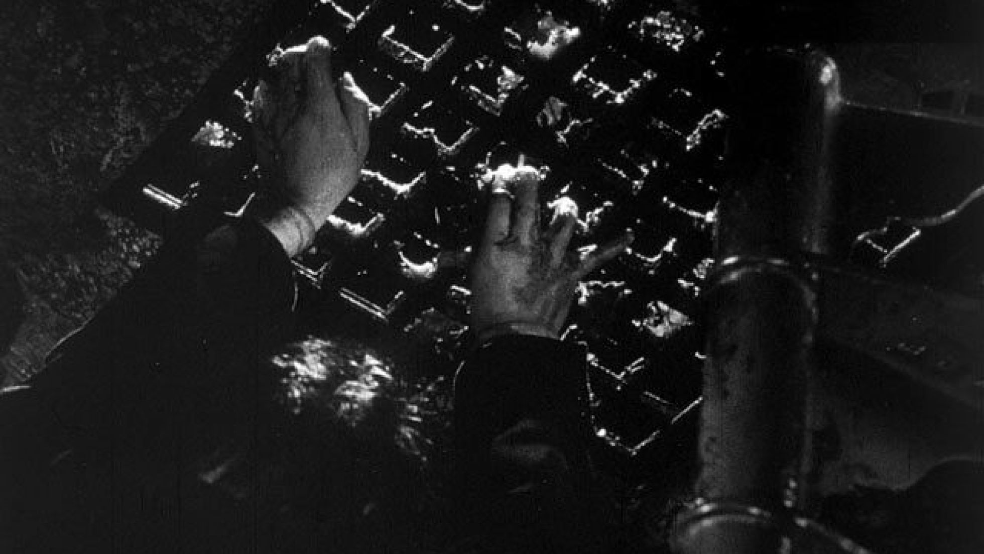 Filmausschnitt: Finger strecken sich von unten durch ein Kanalgitter