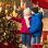 2 Kinder in Winterjacken stehen zwischen Weihnachtsdeko und einem Christbaum.