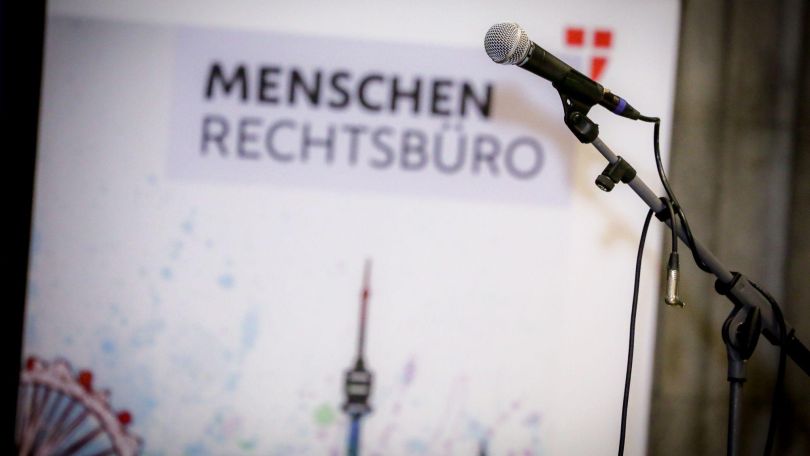 Mikrofon vor Aufsteller mit der Aufschrift "Menschenrechtsbüro"