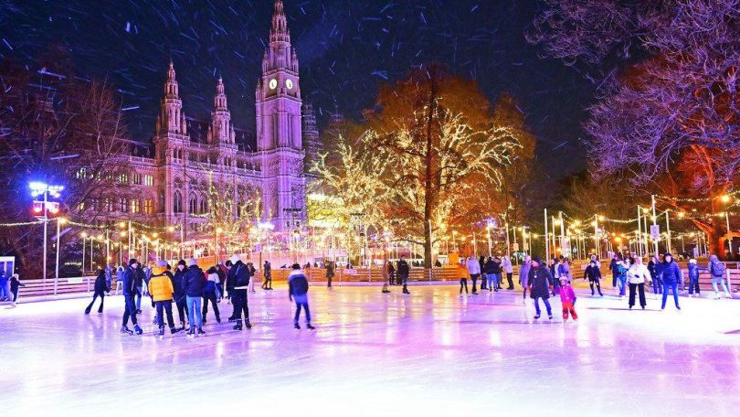 Eislaufplatz am Rathausplatz im Schneegestöber, dahinter das Rathaus