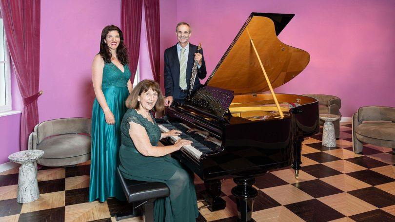 copyright: Dominik Frühauf House of Strauss Trio Clarivoce in einem violetten Raum um einen offenen Flügel