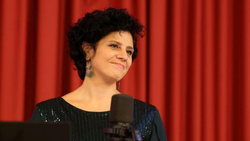 Sopranistin Salpi Lemke steht vor einem roten Vorhang mit einem Mikrofon