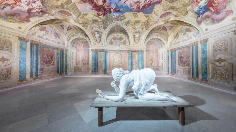 Skulptur einer Frau in einem von Wandmalereien bedeckten Saal