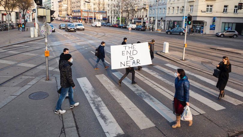 Personen gehen über einen Zebrastreifen mit Schild "Die End is near"