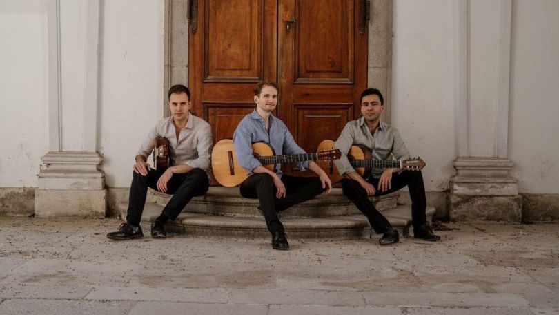 3 Musiker mit Gitarren sitzen auf Stufen