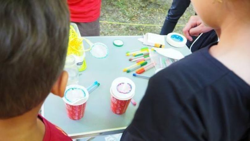 Kinder beim Experimentieren im Park. Sie trennen Farben aus Filzstiften in ihre verschiedenen Bestandteile auf.