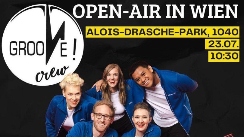 copyright: Groove Crew Fünf Menschen in blauen Hemden lachen in die Kamera, im Hintergrund ein schwarzer Flyer mit Infos zum Event.