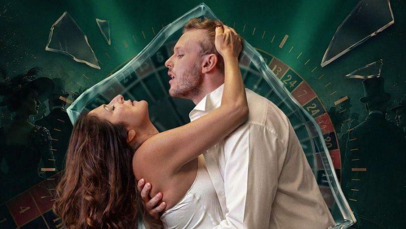 copyright: Karin Svadlenak, Gernot Ottowitz Eine Frau und ein Mann halten sich leidenschaftlich im Arm, hinter ihnen ein Rouletterad und Glasscherben