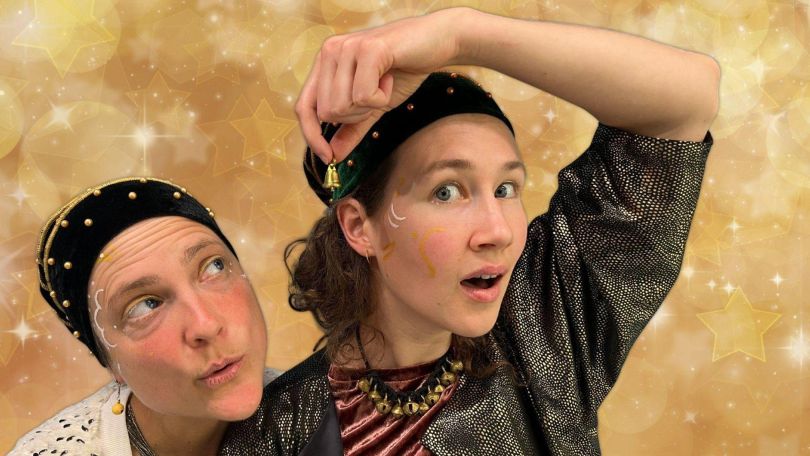 copyright: Töchter der Kunst Zwei Personen in glänzender Kleidung und schwarzen Mützen vor goldenem Sternenhintergrund, eine hält eine kleine goldene Glocke über dem Kopf.