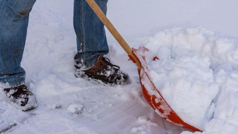 Eine Person räumt mit einer Schneeschaufel Schnee