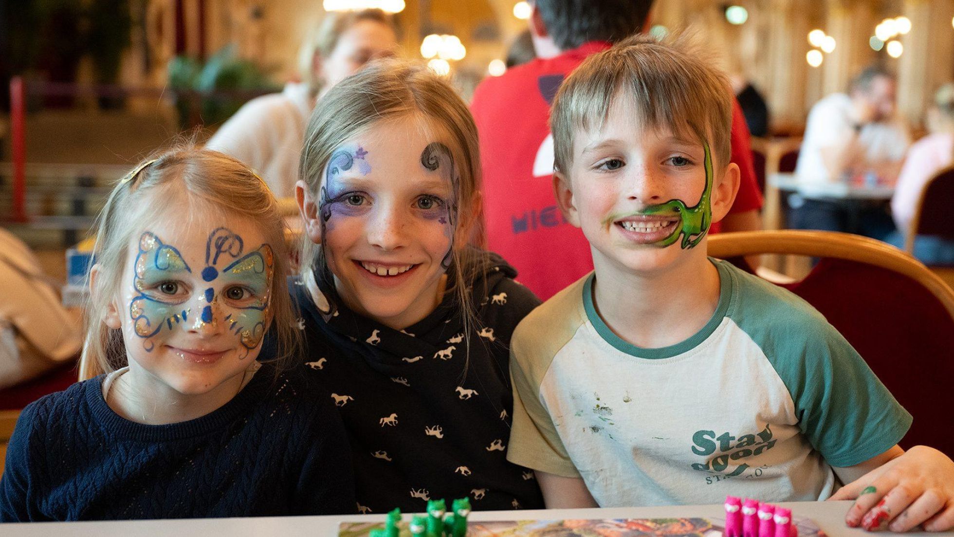 copyright: WIENXTRA/Barbara Mair 3 Kinder mit geschminkten Gesichtern spielen ein Brettspiel.