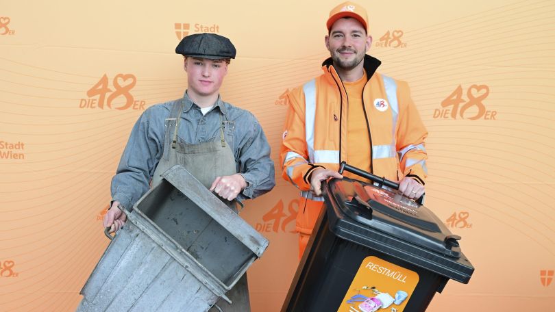 2 Mitarbeiter der MA 48, der Mitarbeiter links in alter Uniform und altem Container und rechts ein Mitarbeiter in neuer Uniform und neuem Container