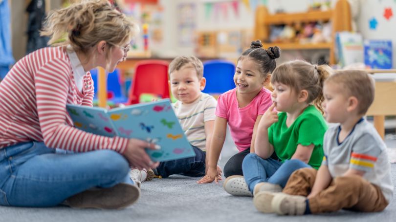 Eine Kindergärtnerin liest Kindern vor