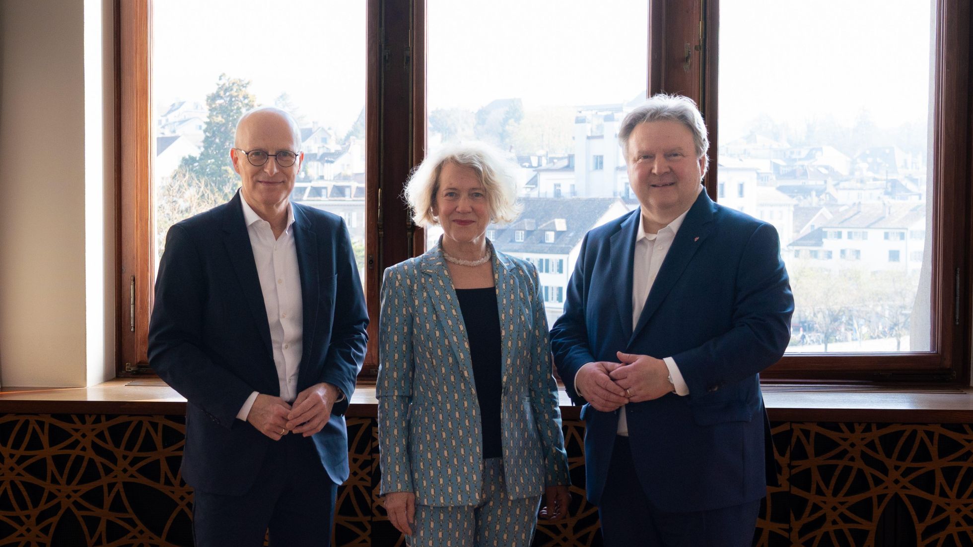 Peter Tschentscher, Corine Mauch und Michael Ludwig posieren zu Dritt für ein Gruppenfoto vor einem Fenster.