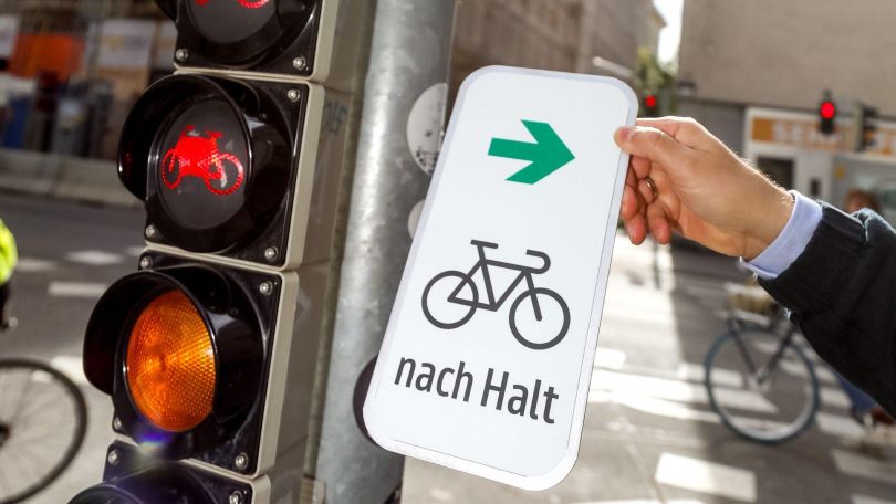 Ampel mit Schild, auf dem sich ein Grünpfeil für Radfahrer*innen befindet