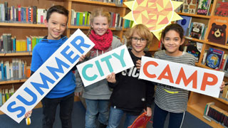Kinder halten Schilder mit "Summer City Camp" hoch