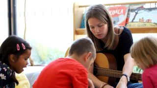 Pdagogin mit Gitarre betreut Kinder