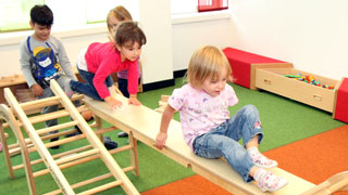 Kinder klettern auf Holzbahnen im Kindergarten
