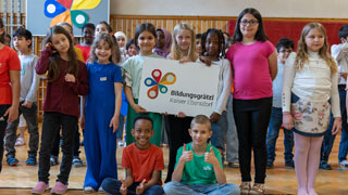 Kinder halten Plakat mit Schriftzug "Bildungsgrtzl Kaiser Ebersdorf" in der Hand