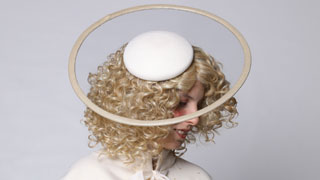 Frau mit goldenen Locken, weiem Umhang und weiem Hut mit Optik eines Heiligenscheins