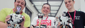Drei junge Forscher mit Robotern