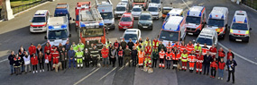 Teamfoto der Helfer Wiens mit Fahrzeugen im Hintergrund
