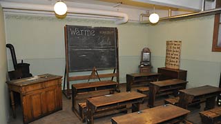 copyright: MA 34 - Bau- und Gebäudemanagement Antiquated schoolroom with desks and black board.